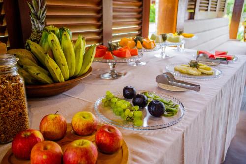 a table with plates of fruit on top of it at AWARA POUSADA BOUTIQUE in São Miguel do Gostoso