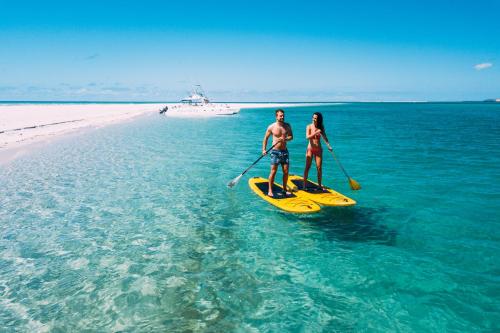 a man and a woman on a paddle board in the ocean at Villa Santorini in Vilanculos