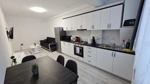 a kitchen with white cabinets and a table and a sink at Nordic Residence 55 in Suceava