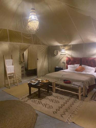 メルズーガにあるMerzouga Luxury Campsのベッドルーム1室(テント、ベッド1台、テーブル付)