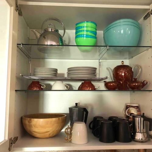 a kitchen shelf with dishes and pots and pans at Stylisches Maybach Appartement mit Terrasse für 5 Personen, 5 Betten, große Kochinsel, Homeoffice mit 250Mbit WLAN in Aidlingen