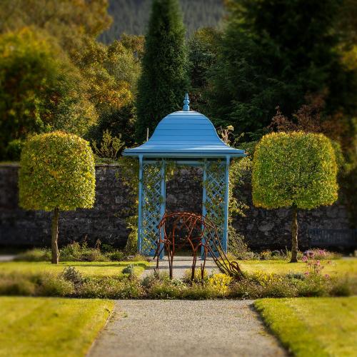 a blue gazebo with a bench in a garden at Inverlochy Castle Hotel in Fort William