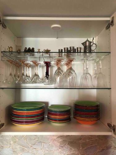 a shelf filled with glasses and plates in a kitchen at Stylisches Maybach Appartement mit Terrasse für 5 Personen, 5 Betten, große Kochinsel, Homeoffice mit 250Mbit WLAN in Aidlingen