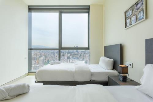 1 Schlafzimmer mit 2 Betten und einem großen Fenster in der Unterkunft Denim 3 Bedroom Apartment With Pool in Beirut