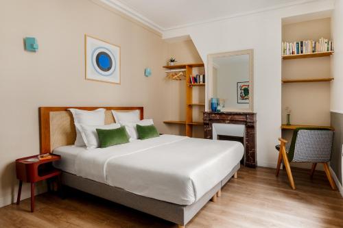 una camera da letto con un grande letto bianco con cuscini verdi di Edgar Suites Grands Boulevards - Hauteville a Parigi