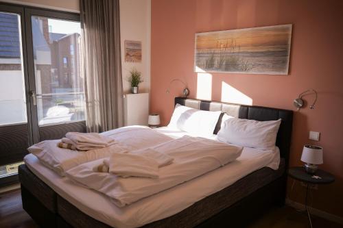 ハイリゲンハーフェンにあるOstsee - Appartement Nr 68 "Utspann" im Strand Resortのベッドルーム(白いシーツと枕付)