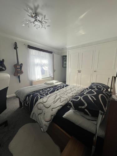 a bedroom with two beds and a guitar on the wall at Private Flat in City Centre with Parking in Southampton