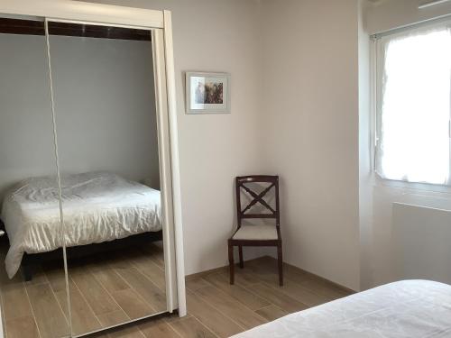 a mirror in a bedroom with a bed and a chair at Villa bord de mer in Loctudy
