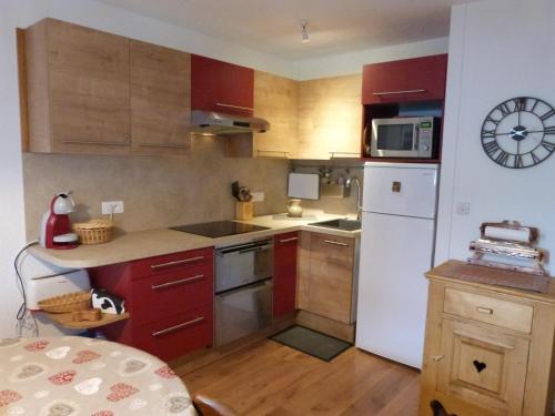 a kitchen with red cabinets and a white refrigerator at T2 au coeur de Praloup - Le Chanteval in Uvernet