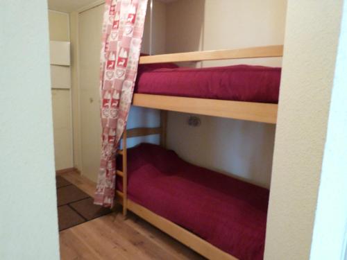 a room with two bunk beds with red sheets at T2 au coeur de Praloup - Le Chanteval in Uvernet