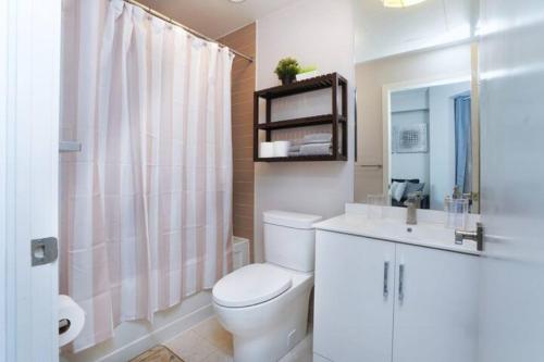 a white bathroom with a toilet and a sink at Simply Comfort Suites - One plus Den Apartment with Scotiabank Arena View in Toronto