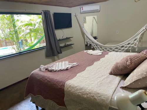 a bedroom with a bed and a window with swings at Safira Beach House in Pipa