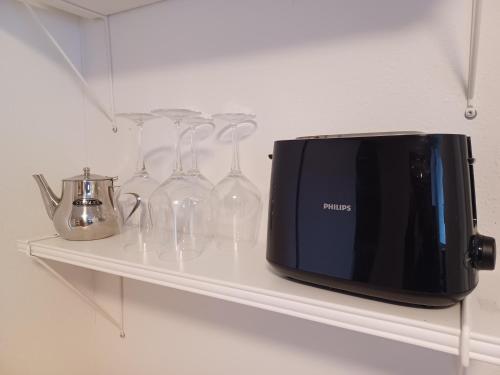 a shelf with wine glasses and a toaster on it at Kleine Galerie Apartment für 3 mit Küche Kamin Netflix Parken und Hofladen in Steinhöfel