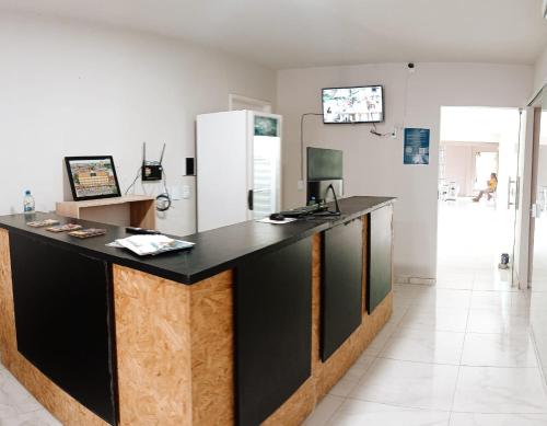 a kitchen with a black counter and a refrigerator at Hotel Aconchego Cearense in Fortaleza