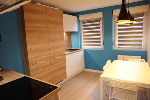 une cuisine avec une table blanche et un mur bleu dans l'établissement L'Insoupçonné : garage, proche Axone, Stellantis, à Audincourt