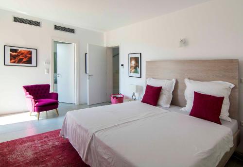 1 dormitorio con 1 cama blanca grande con almohadas rojas en White Pearl Golf Villa, en Gialova