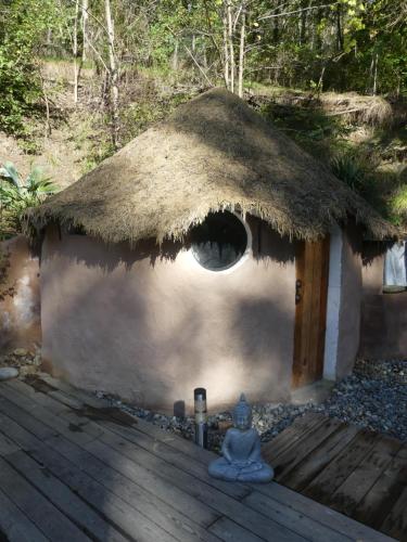 a hut with a thatched roof and a wooden deck at Gite unique et piscine privative dans un écrin de verdure in Culmont