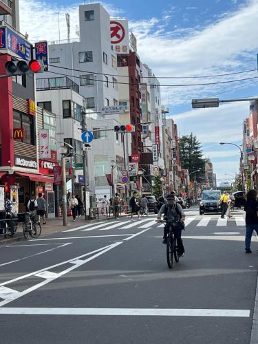 a man riding a bike down a busy city street at Lucky Hotel in Tokyo