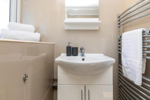 a white bathroom with a sink and towels at 19A Apartment- Stylish & Cozy 1BR in The Heart of Crawley in Crawley