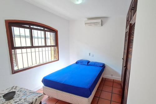 a bedroom with a blue bed and a window at Linda Casa com Piscina - Praia do Pernambuco - Guarujá in Guarujá