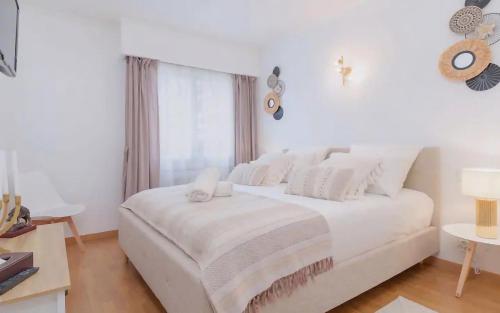 un lit blanc dans une chambre blanche avec une fenêtre dans l'établissement Le Concorde - Charmant appt avec terrasse, à Cannes