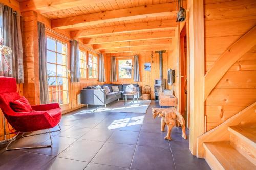 a living room with red chairs and a dog in it at Chalet Collini in Riederalp