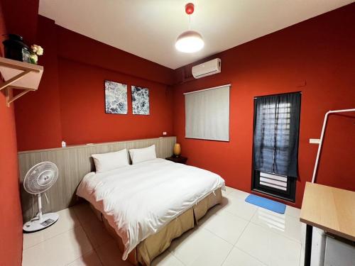 a bedroom with a white bed and red walls at 好客行館 in Donggang