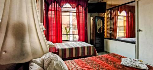 a bedroom with two beds and a window with red curtains at HOTEL KEYMAR SPA in Moquegua