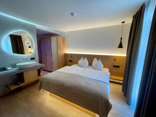 um quarto com uma cama, um lavatório e um espelho em Hotel Des Alpes em Selva di Val Gardena