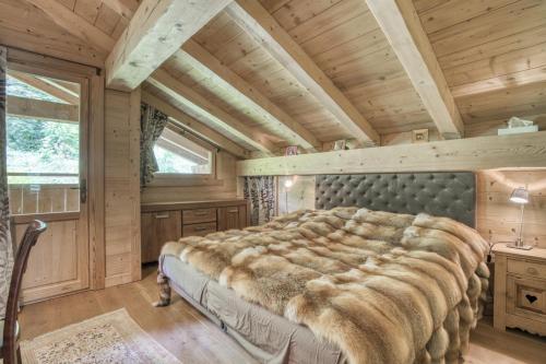 Cama grande en habitación con techo de madera en Chalet luxe MARTA en Saint-Laurent-de-Mure