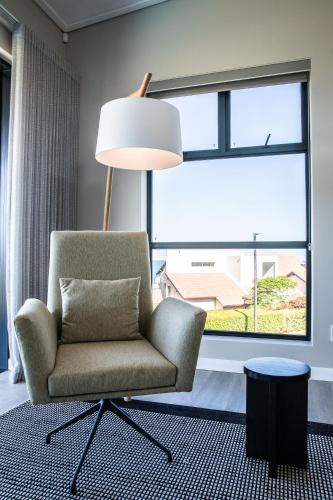 a chair and a lamp in a room with a window at Hilltop Bayview Luxury Apartments in Plettenberg Bay