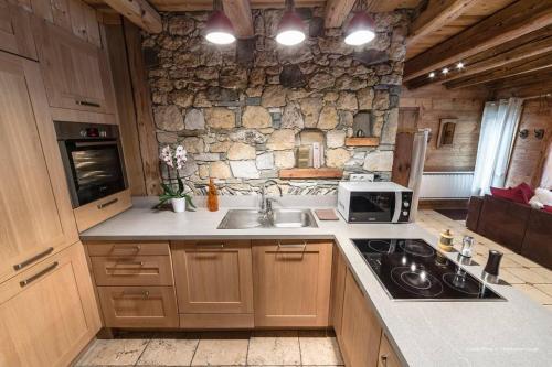 une cuisine avec un évier et un mur en pierre dans l'établissement Chalet Ancolie, à Val dʼIsère