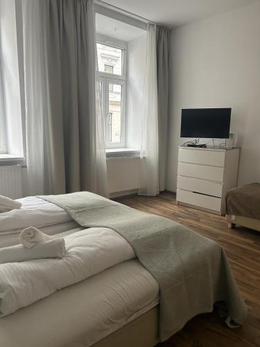 a white bedroom with a bed and a television at Cozy City Center Apartments in Vienna