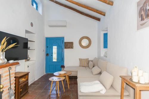 a living room with a white couch and a blue door at Finca Rosalia in Cómpeta