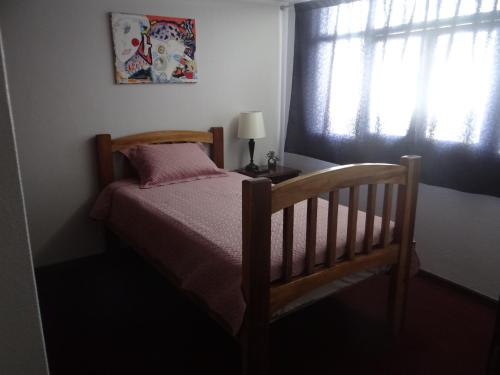 een slaapkamer met een bed met een lamp en een raam bij San Antonio Inn in Quito