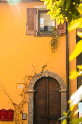 a yellow building with a wooden door and a window at Suite Cielo - Lago di Como in Blevio