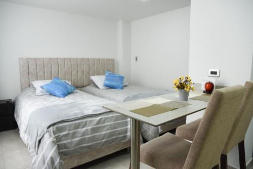 1 dormitorio con cama y mesa con almohadas azules en Apartaestudios, La Castilla Avenida de los Estudiantes, en Pasto