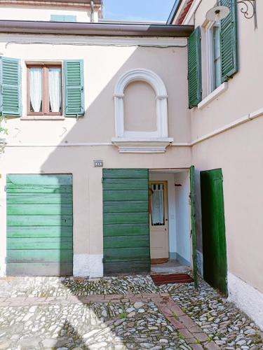 a white house with green doors and windows at Appartamento Ancella - Residenza la Madonina Morciano in Morciano di Romagna