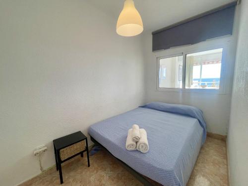 um quarto com uma cama com duas toalhas brancas em Caballos Levante Beach em Benidorm