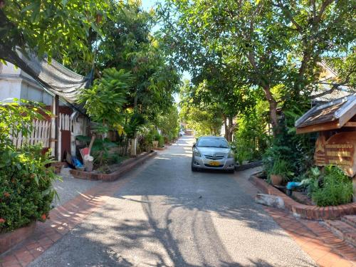 a car parked on a street next to houses at watthat & Maladress GUESTHOUSE in Luang Prabang