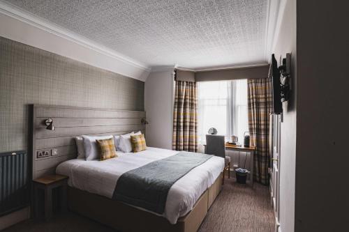 a bedroom with a large bed and a window at Tullie Inn in Balloch