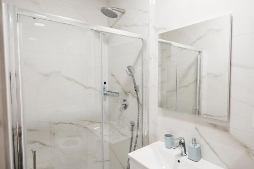 a white bathroom with a shower and a sink at KM Apartments in Zagreb