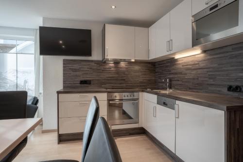 a kitchen with white cabinets and a counter top at Petit Madlein in Ischgl
