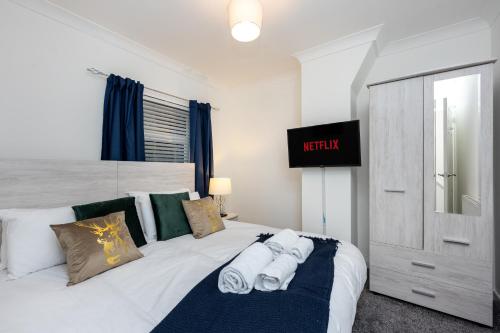 a bedroom with a white bed with towels on it at King Beds - Smart TVs - Parking - Near City in Swansea