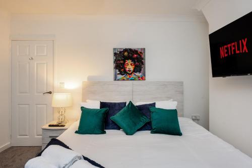 a bedroom with a white bed with green pillows at King Beds - Smart TVs - Parking - Near City in Swansea