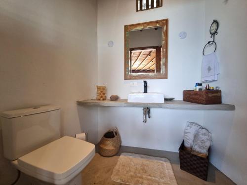uma casa de banho com um WC, um lavatório e um espelho. em Casa com piscina de borda infinita em Ilhabela em Ilhabela