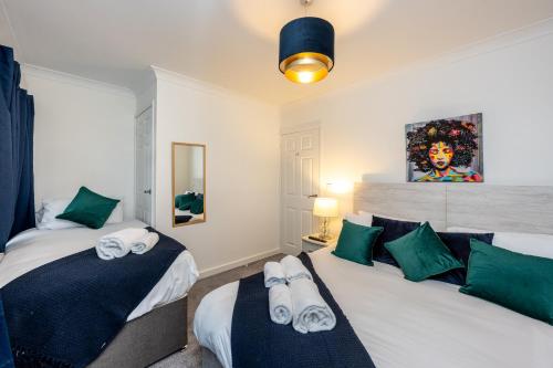 una camera con 2 letti con cuscini verdi e bianchi di Horeb House TV in every bedroom! a Morriston