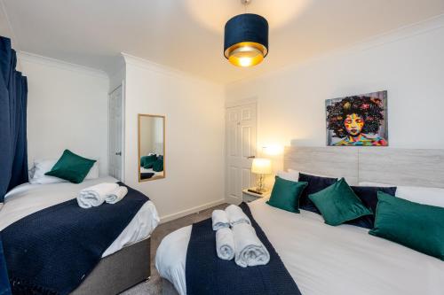 a bedroom with two beds with green and white pillows at King Beds - Smart TVs - Parking - Near City in Swansea