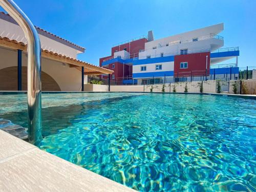 une piscine devant un immeuble dans l'établissement SELECT'SO HOME - Résidence Le Poséidon - Piscine & Garage - Prestations de qualité & Services Hôteliers - POS22, à Bormes-les-Mimosas
