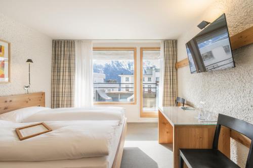 Hauser Hotel St. Moritz في سان موريتز: غرفة فندقية بسريرين ونافذة